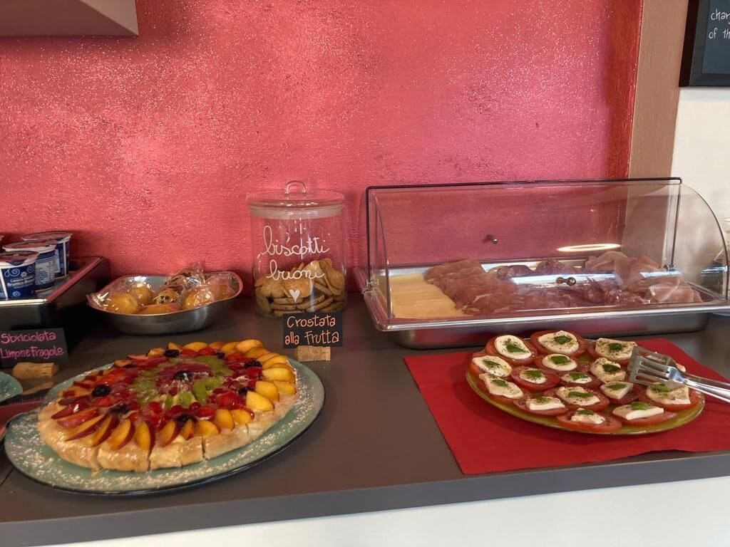 Un buffet con diversi piatti, tra cui pizza, crostata di frutta e altri dolci.