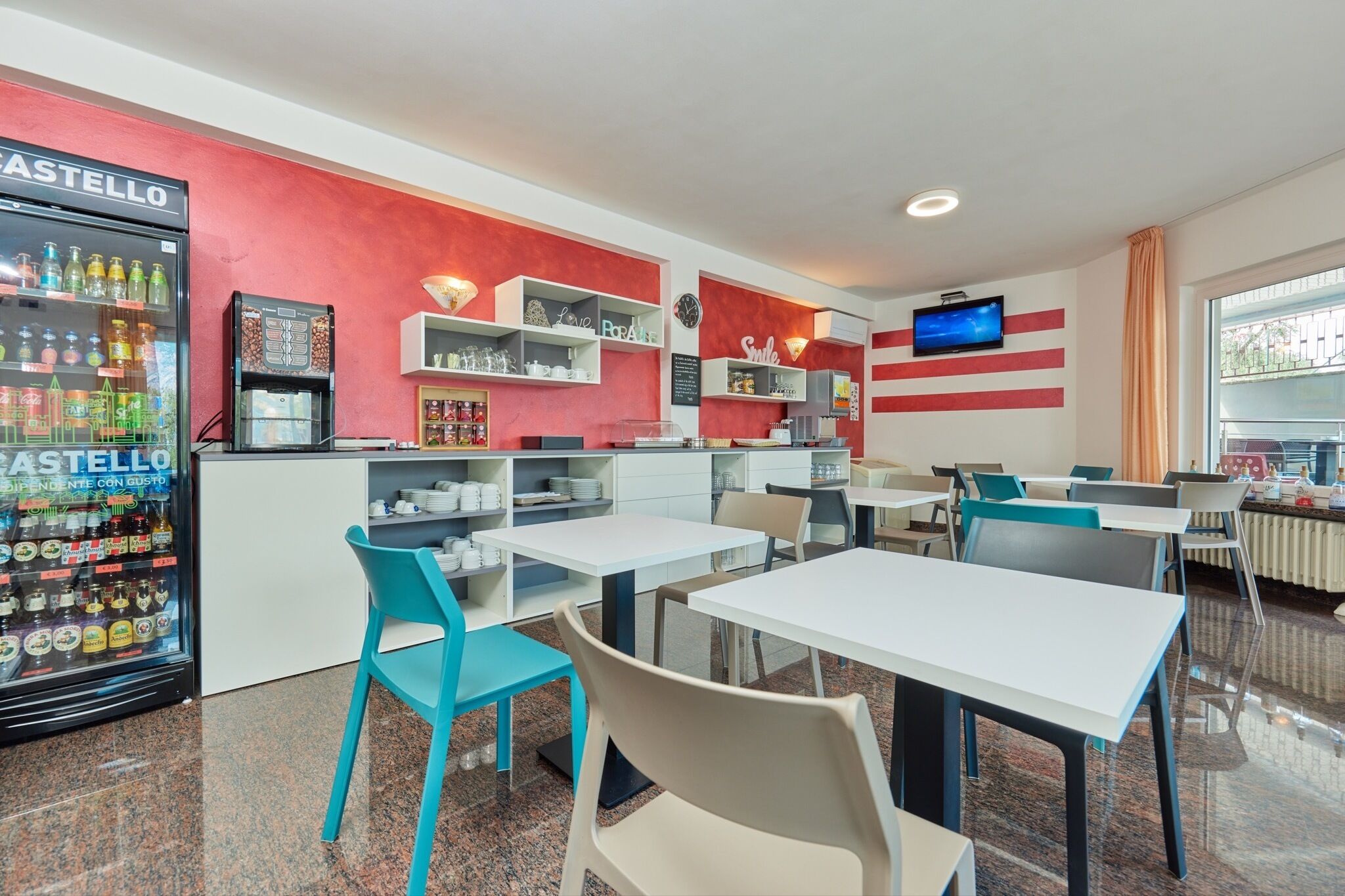 A modern restaurant with a red and white color scheme, featuring a self-service beverage station, multiple tables, and chairs.