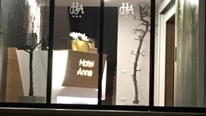 A hotel entrance with a sign reading "Hotel Anna" and a modern design with glass doors and a staircase leading inside. - Hotel Anna (Malcesine)