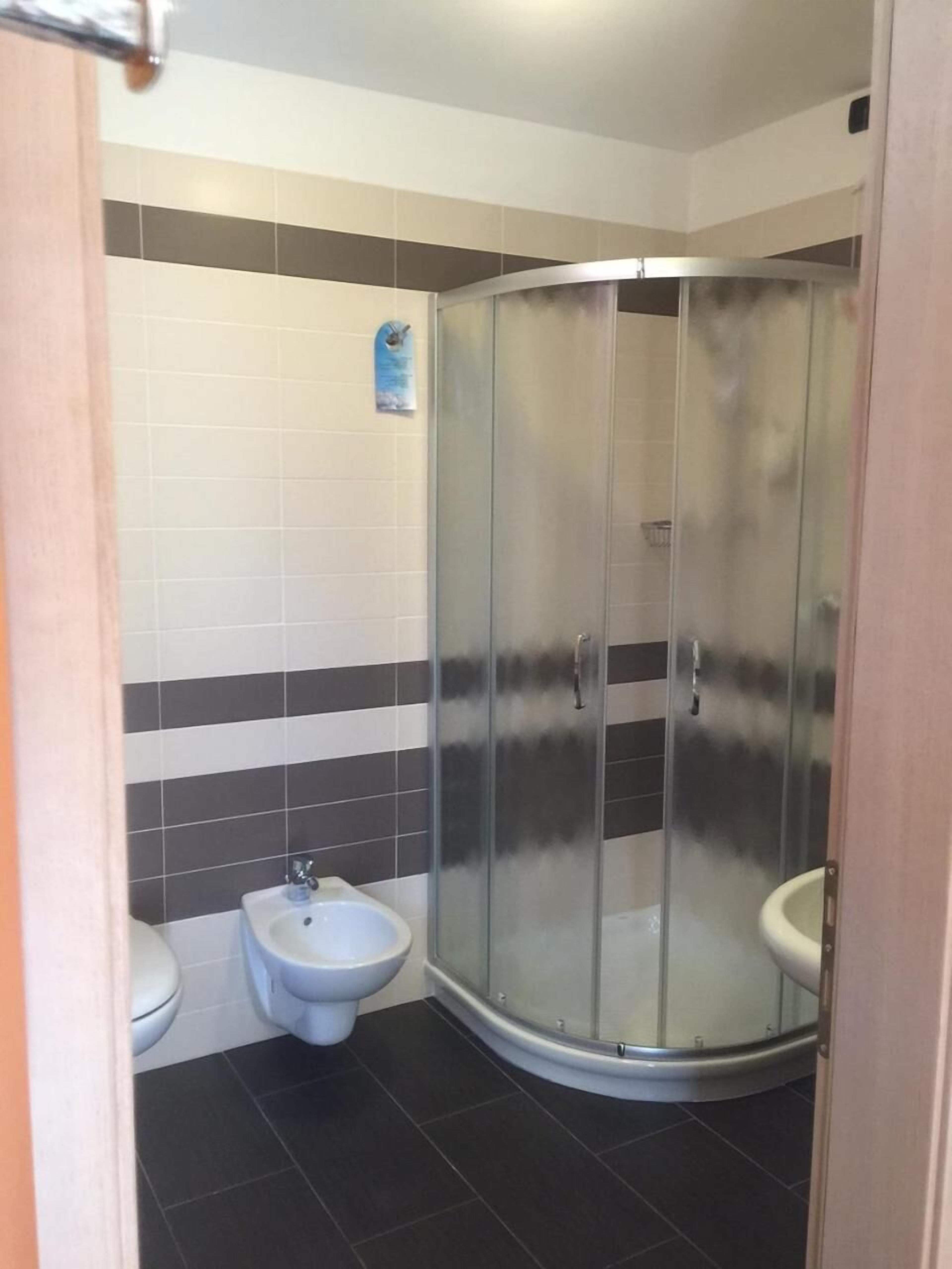 A bathroom with a glass-enclosed shower, a bidet, and a toilet.