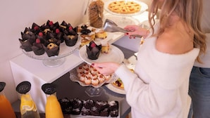 Una mesa de buffet con diversos postres y una persona sirviendo comida.