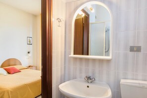Une chambre d’hôtel comprenant un lit, une table de chevet, un miroir, un lavabo et des toilettes.