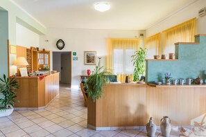 Un espace d’accueil avec un bureau en bois, une horloge au mur et une plante en pot.