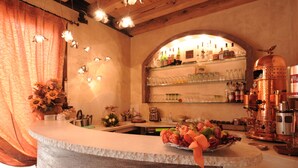 A bar area with a counter, shelves with glasses and bottles, and a copper espresso machine.