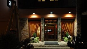 A hotel entrance with a stone facade, two doors, and a small step leading up to the entrance.