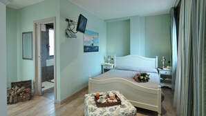 A bedroom with a bed, bedside tables, a television, and a breakfast tray on a small table.