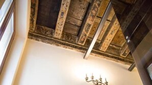A staircase with a metal handrail, wooden beams, and framed pictures on the wall. - Hotel al Castello (Verona)