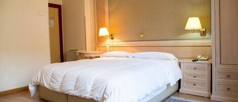 A hotel room with a bed, nightstands, a telephone, and a patterned rug.