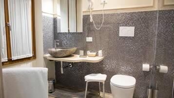 Ein modernes Badezimmer mit einem Steinsink, einer Toilette und einer Dusche.