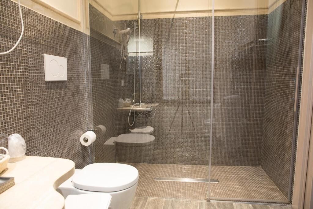 Een moderne badkamer met een douchecabine van glas, een toilet en een wastafel.