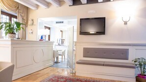 A modern living room with a fireplace, a television mounted above it, and a dining area in the background. - Hotel al Castello (Verona)