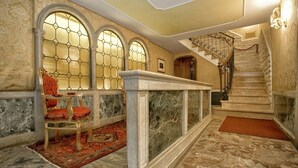 A grand hallway with a marble floor, a red carpet, and a staircase with a wrought iron railing. - Hotel Noemi (Venice)