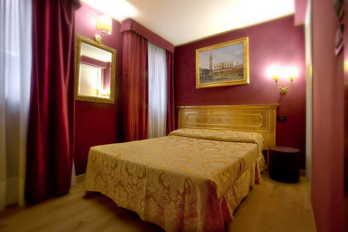A hotel room with a large bed, a wooden headboard, a round side table, and a painting on the wall.