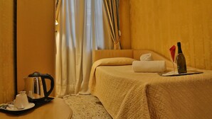 A hotel room with a bed, a bedside table with a kettle, a wine bottle, and a glass. - Hotel Noemi (Venice)