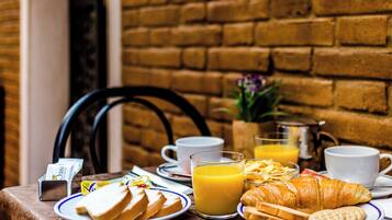 Une table de petit-déjeuner avec des assiettes remplies de nourriture, des tasses et un verre de jus d’orange.