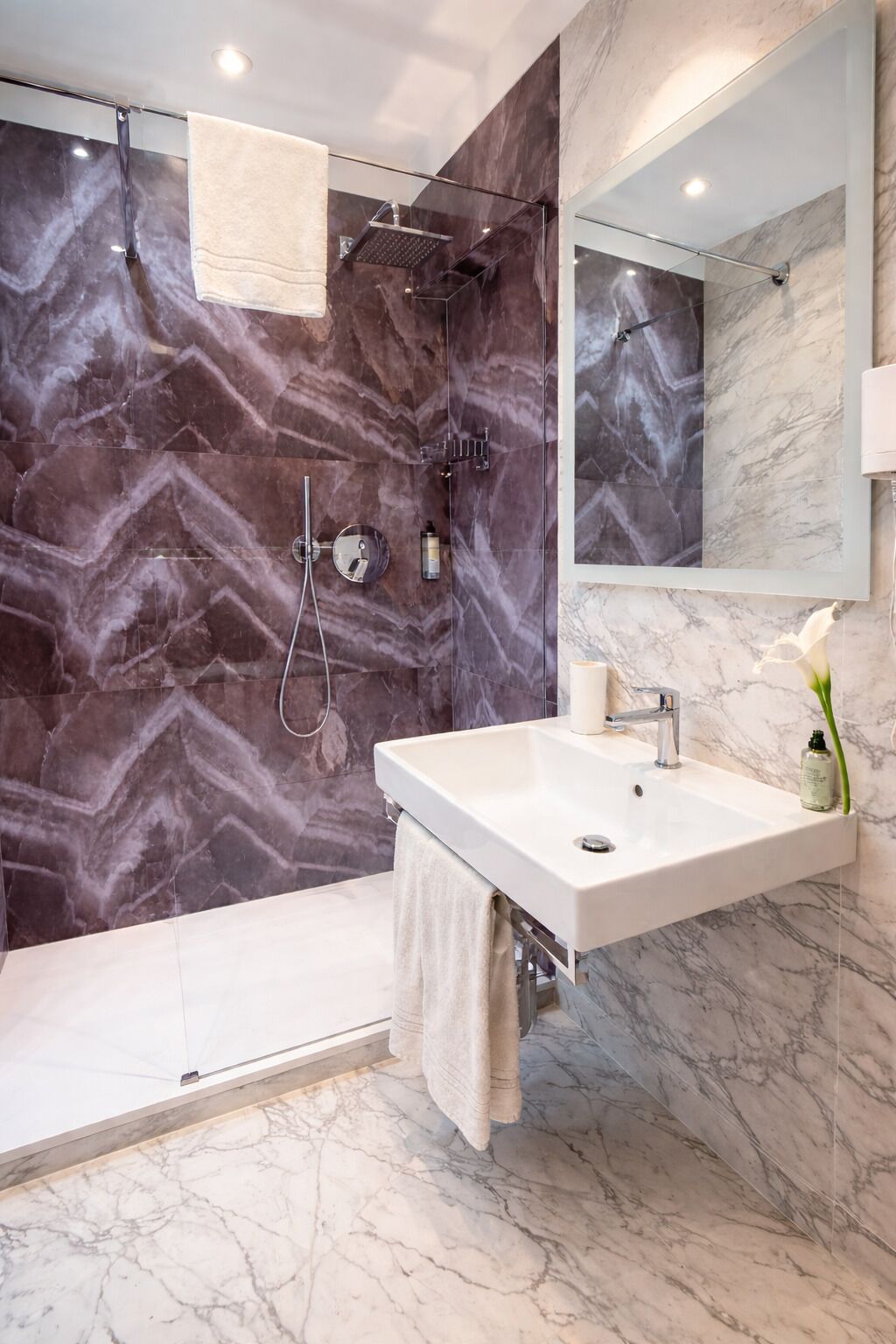 A modern bathroom with a shower, a sink, and a mirror.