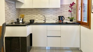 Une cuisine moderne avec des meubles blancs, un plan de travail noir et un pare-feu en carrelage.