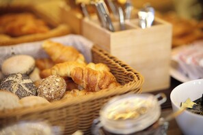 A variety of baked goods including bread, croissants, and pastries in a wicker basket. - Locanda Silva (Venice)