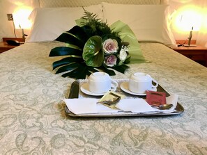 A neatly arranged breakfast tray on a bed with a floral arrangement and two cups of tea. - Locanda Silva (Venice)