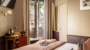 Une chambre d’hôtel équipée d’un lit, d’un bureau, d’une chaise, d’une machine à café et d’une fenêtre avec des rideaux.