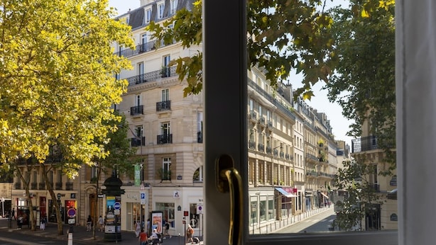 Une vue de rue avec une rangée de bâtiments européens classiques, un passage piéton et un arrêt de bus.