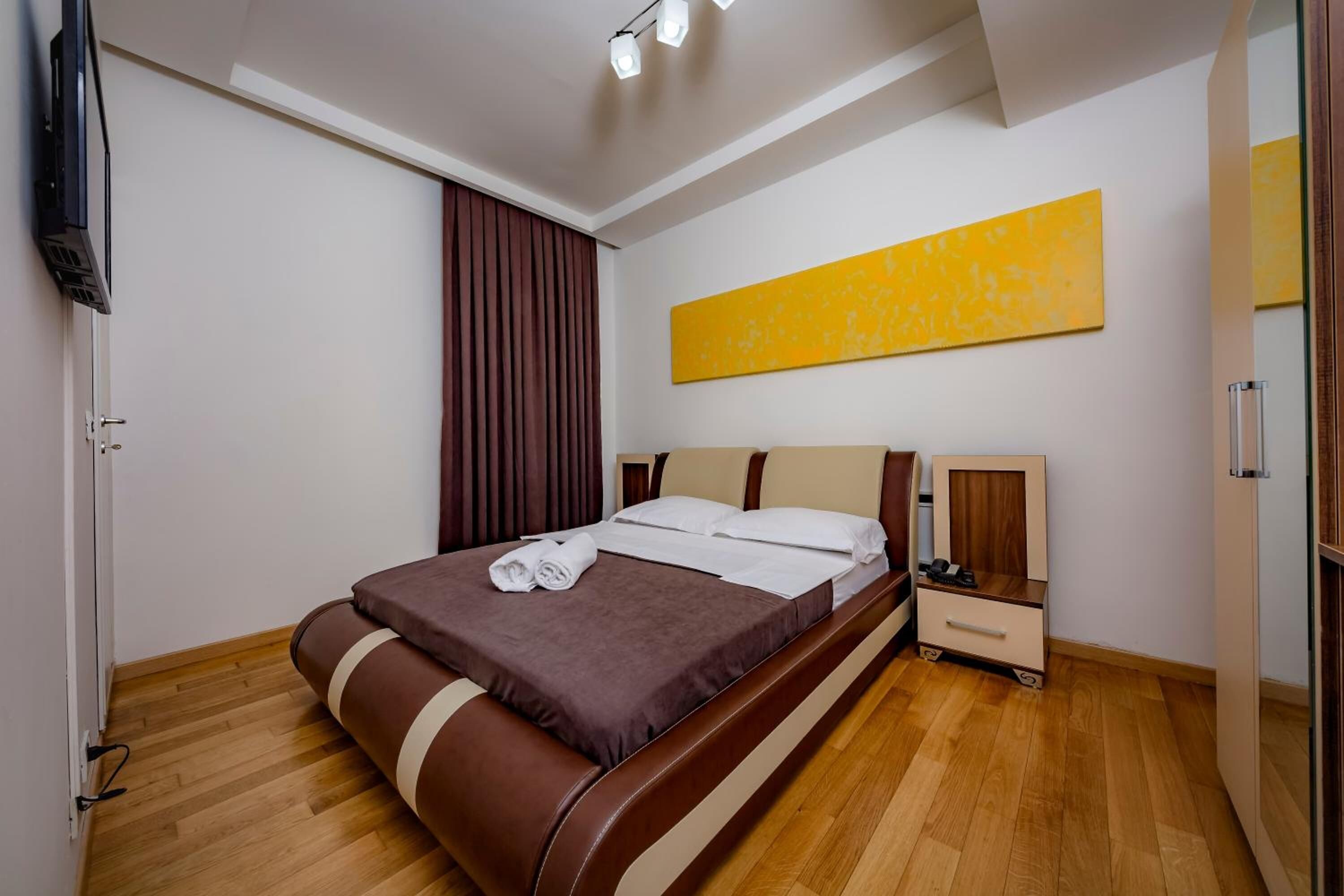A modern hotel room with a bed, bedside table, and a large window with curtains.