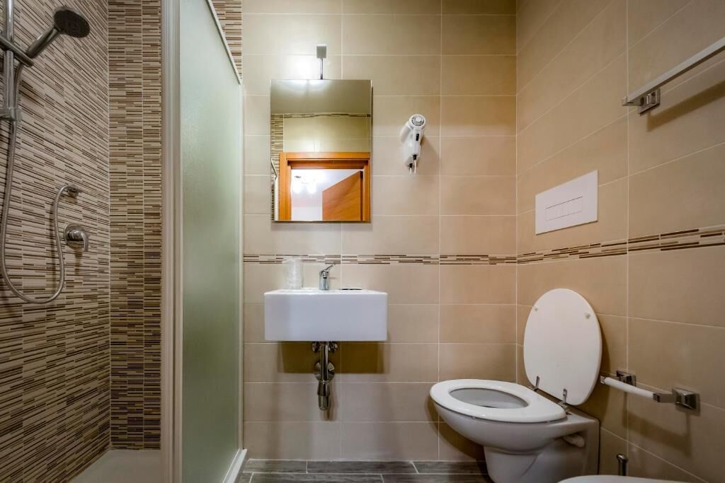 Un bagno con doccia, lavandino e WC.