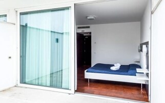 Una camera da letto moderna con un letto, un comodino e una finestra con tende.