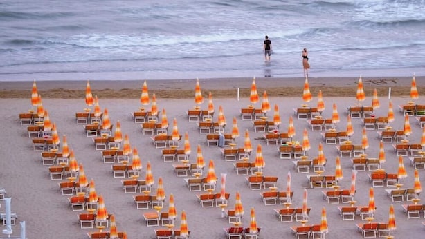 A beach with rows of sun loungers and beach umbrellas.