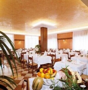 A banquet hall with multiple round tables covered with white tablecloths, arranged in rows. - Hotel Sole (Eraclea)