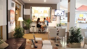 A bar area with a counter, seating, and a television screen. - Hotel Moderno (Jesolo)