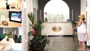 A hotel lobby with a reception desk, a large mirror, and a potted plant. - Hotel Moderno (Jesolo)