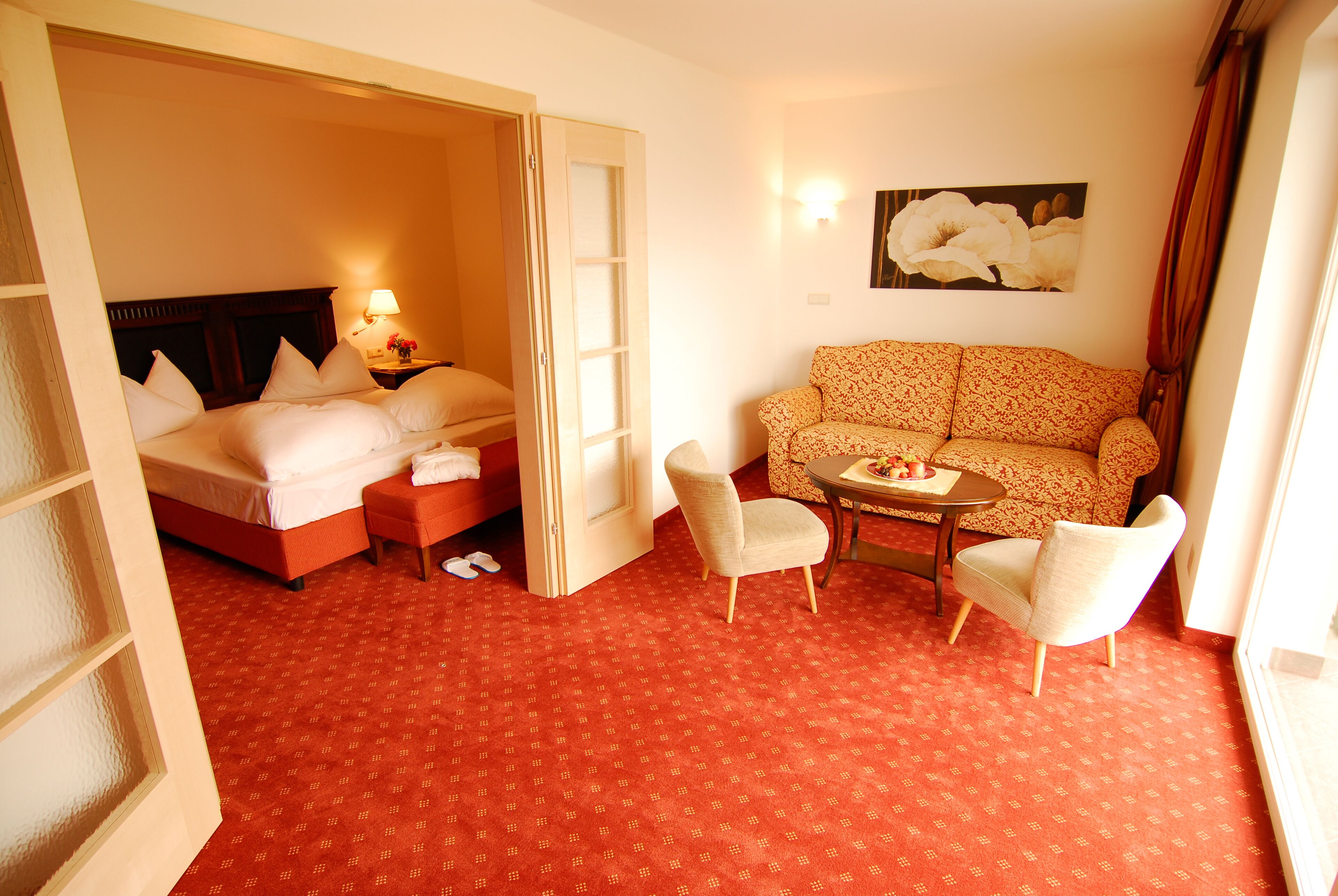 A hotel room with a bed, a sofa, a small table, and a chair.