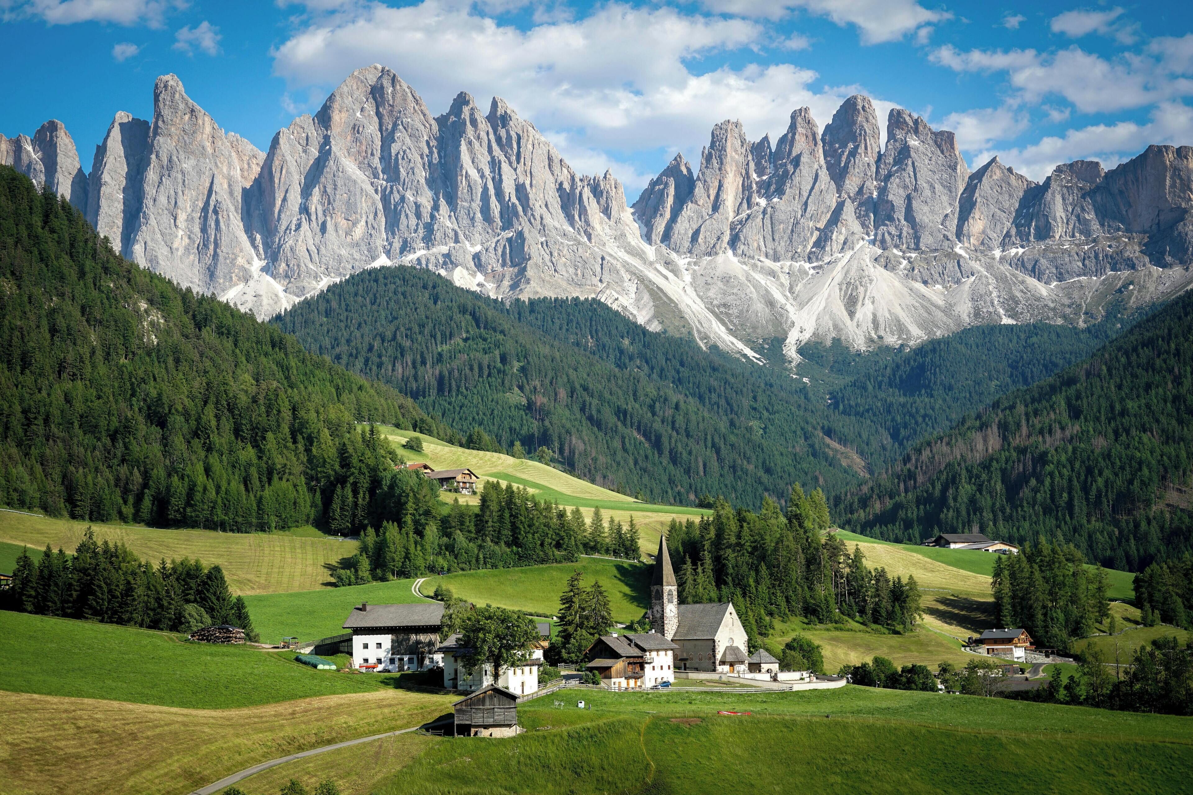 A mountain village with a church, houses, and a road leading up the valley.
