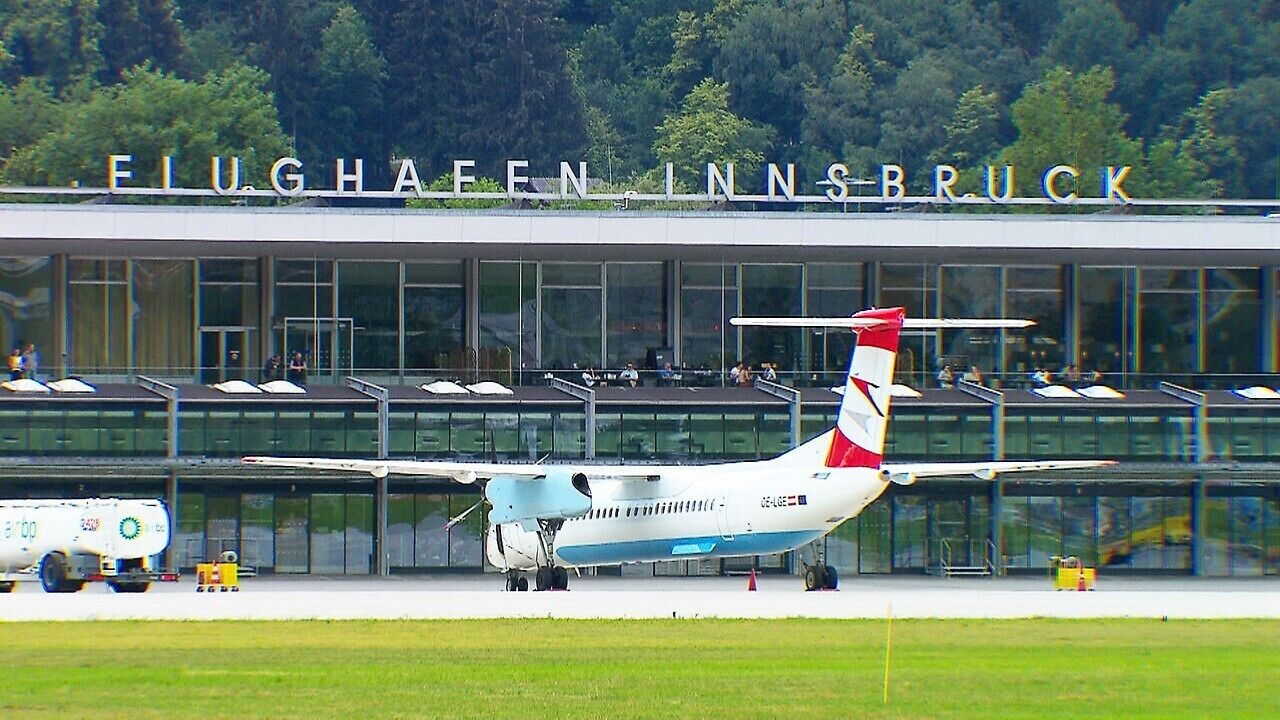 Un avión estacionado frente a un edificio con el letrero "ELUGHAEN INNSBRUCK".