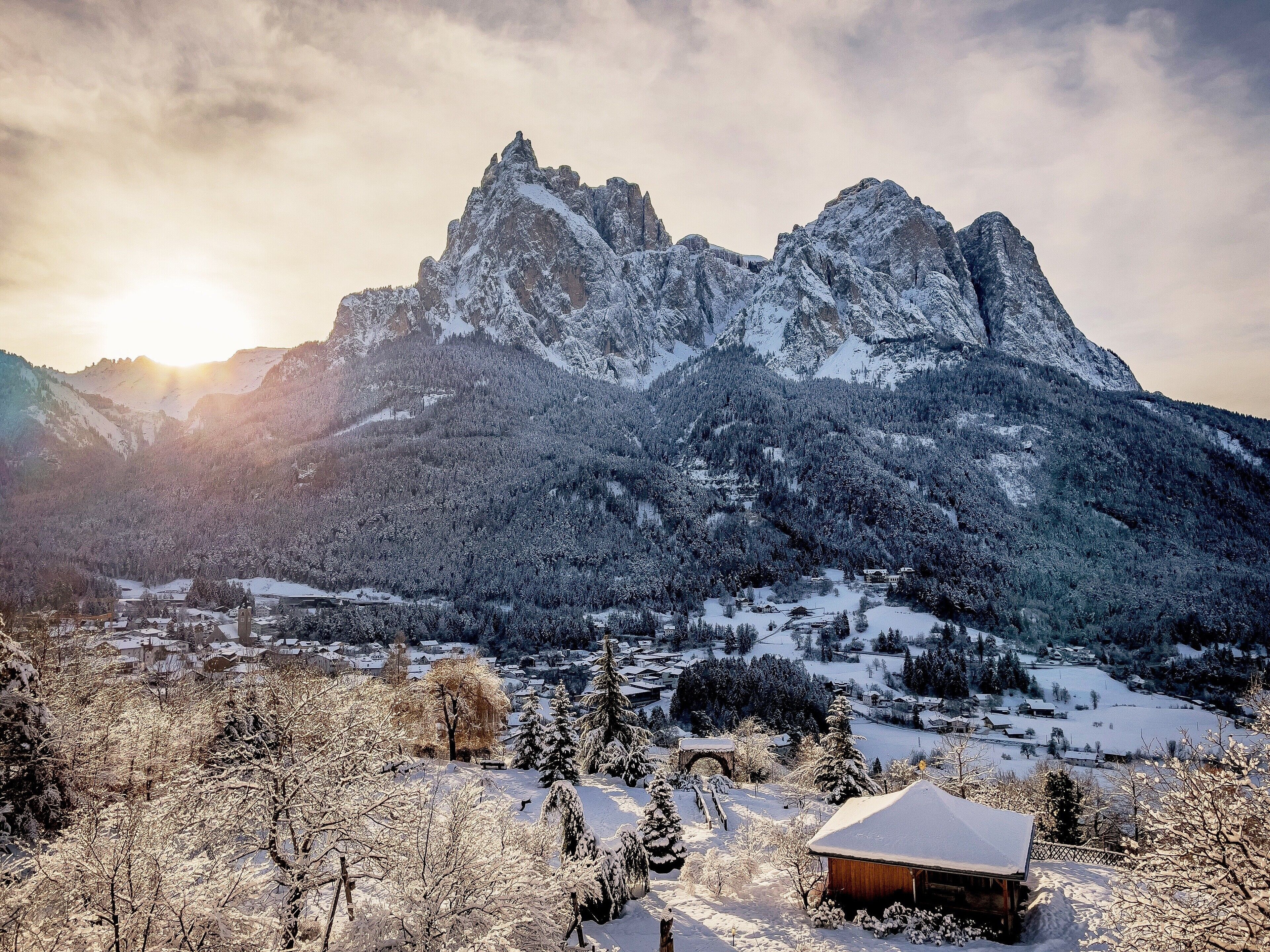 A mountain landscape with a wooden cabin in the foreground.