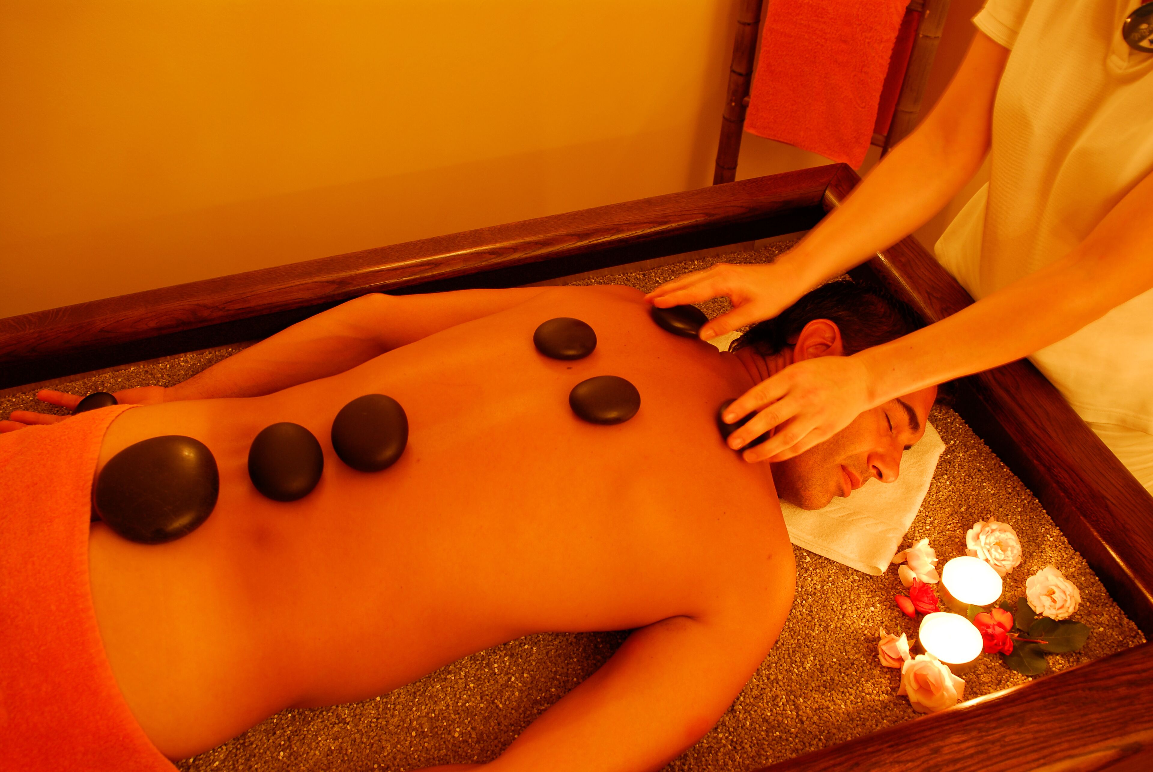 A person receiving a stone massage with several stones placed on their back.