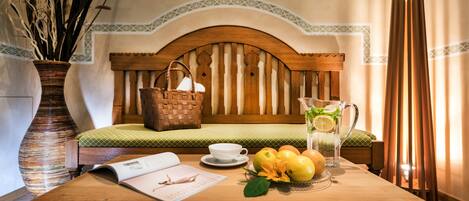 Una mesa de madera con una revista, una jarra de limonada y una cesta de fruta.