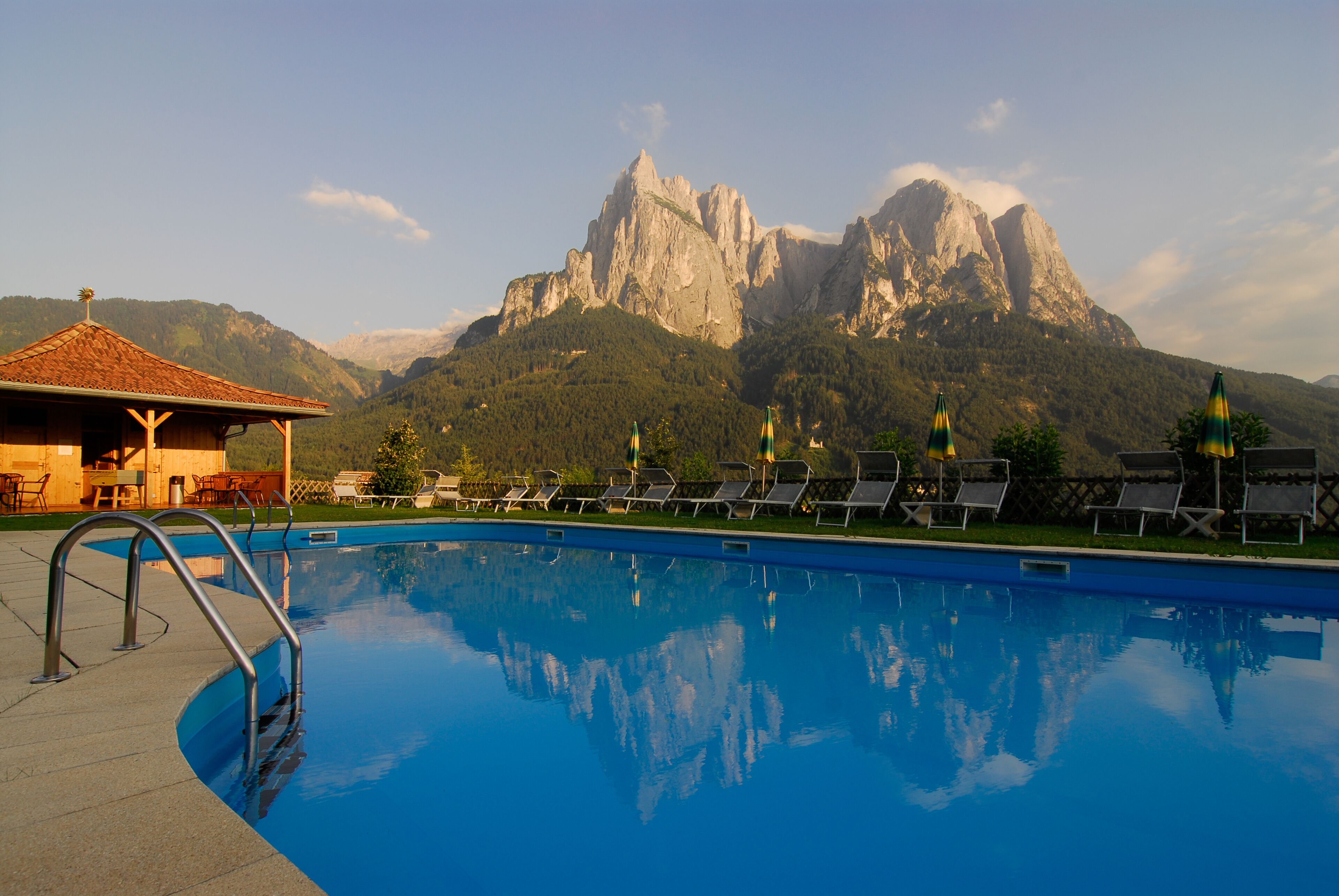 A swimming pool with lounge chairs and a mountain backdrop.