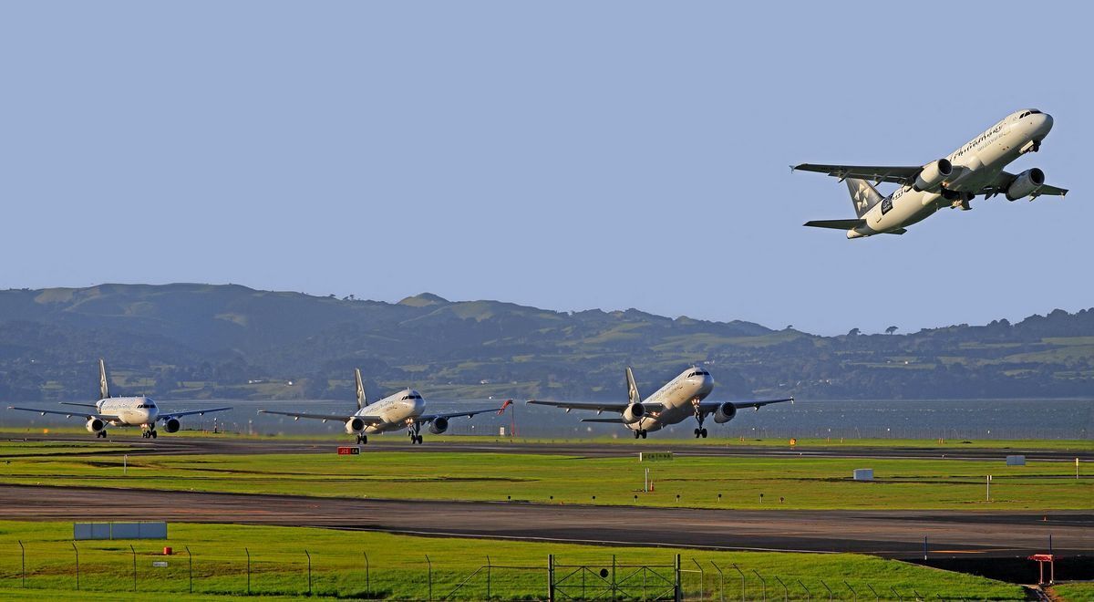 An airport runway with multiple airplanes in various stages of takeoff and landing.