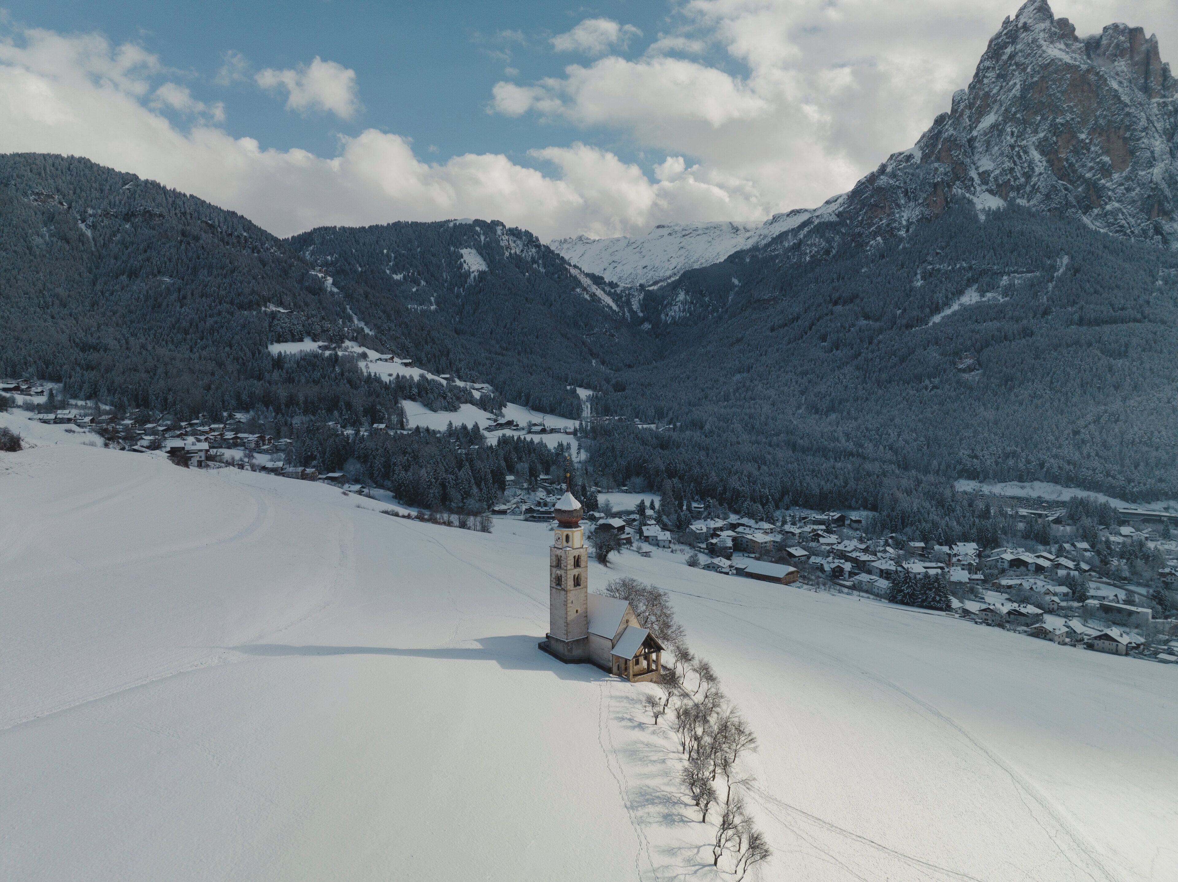 A snow-covered landscape with a small village and a church tower.