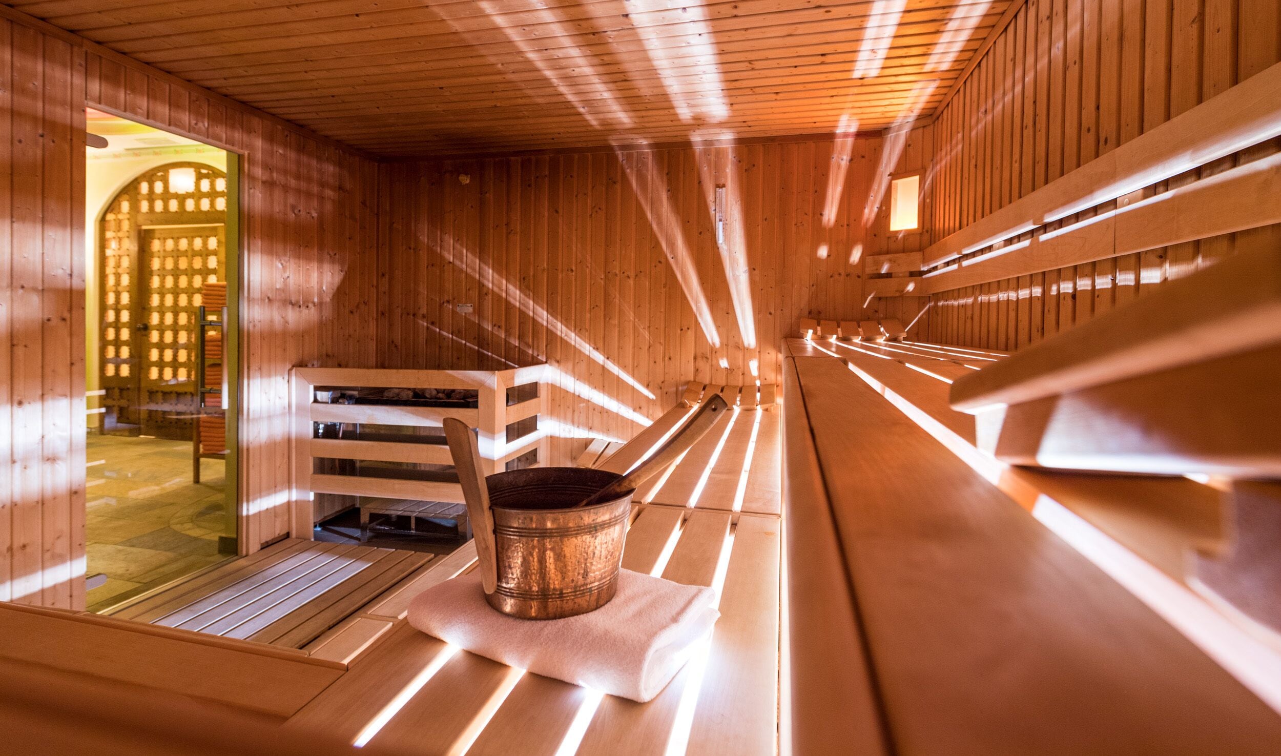 Sauna, jossa on puiset lauteet ja kuparinen ämpäri.