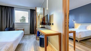 Habitación de hotel con dos camas, un escritorio, un televisor y una ventana.