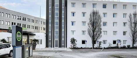 Un hotel moderno con una torre central, un estacionamiento y un cartel.