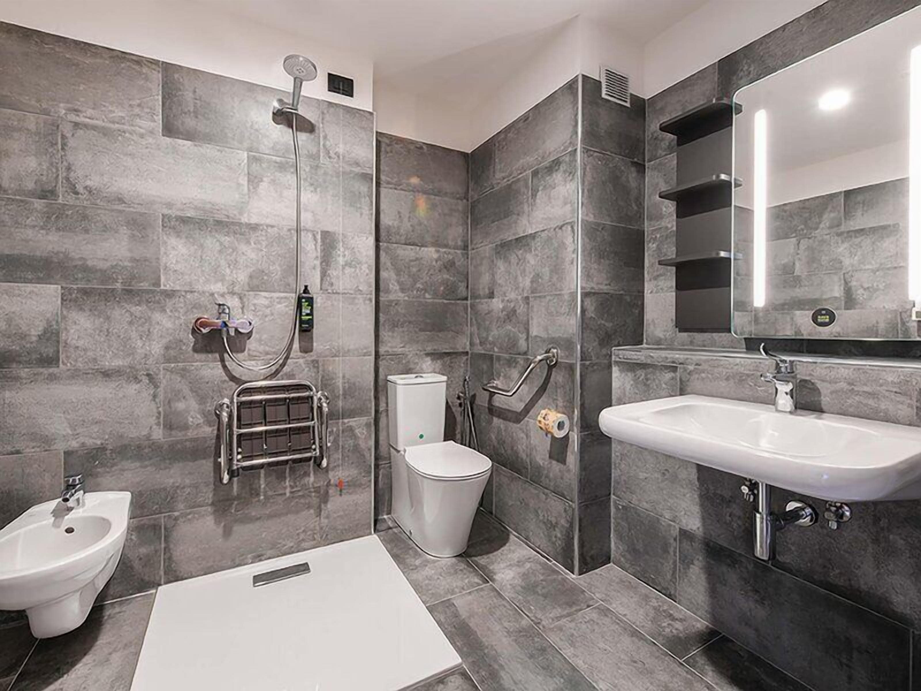 A modern bathroom with a shower, bidet, sink, and toilet.