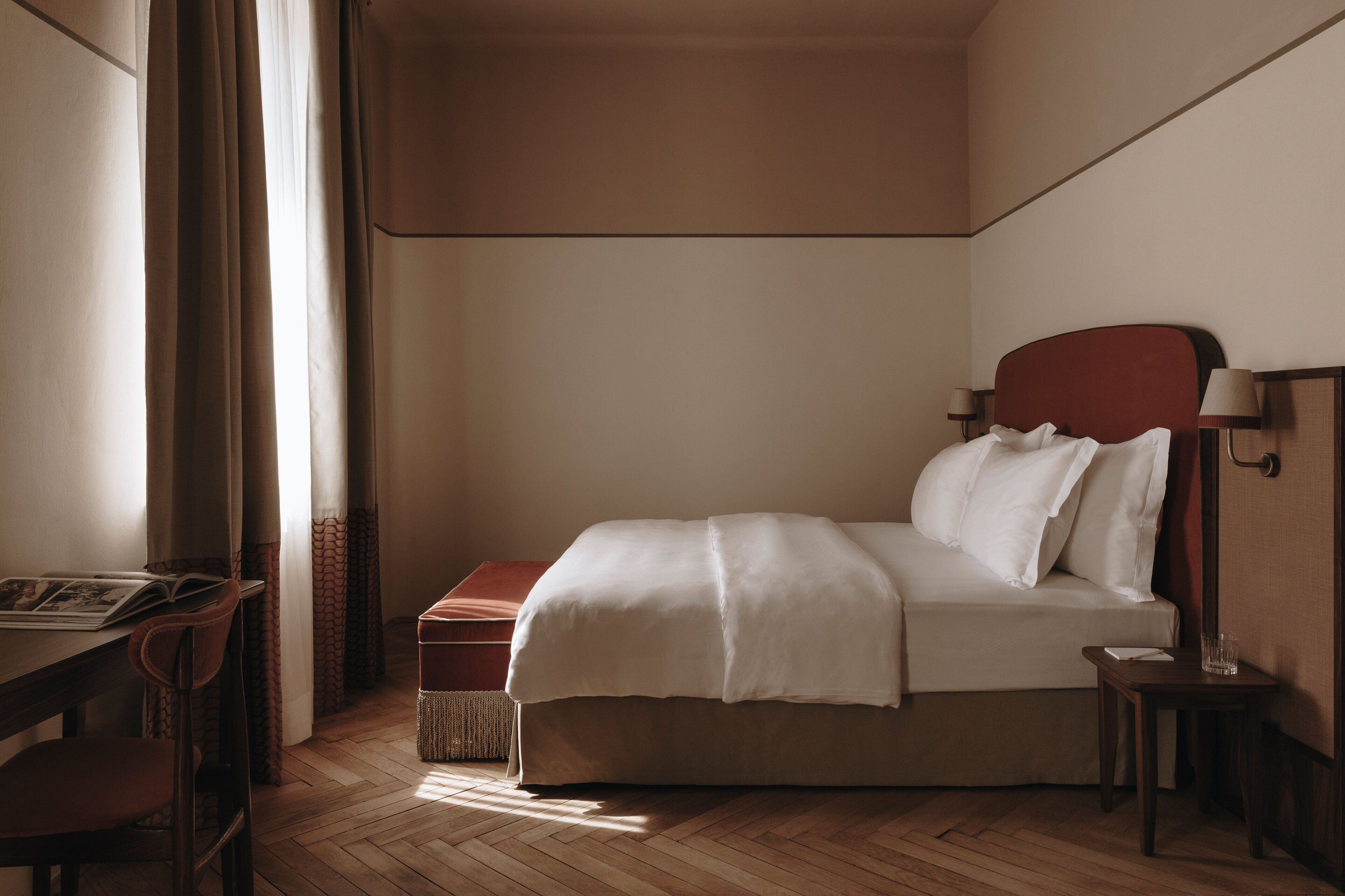 Siististi järjestetty hotellihuone, jossa on sänky, työpöytä ja tuoli.
