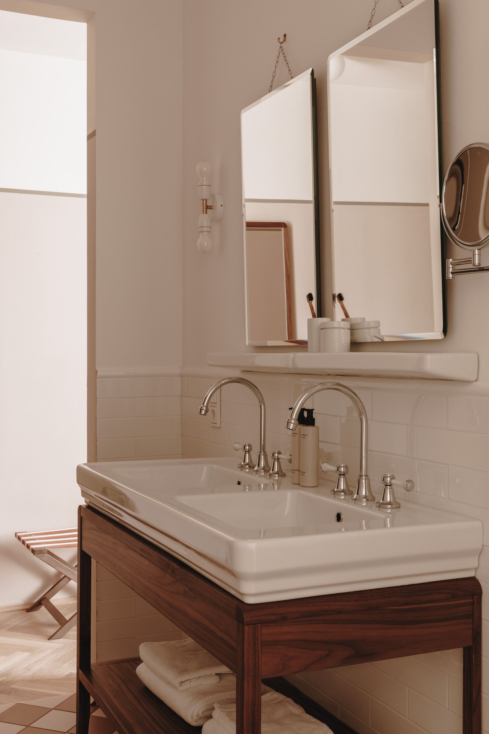 A bathroom with a double sink, wooden vanity, and a large mirror above the sink.
