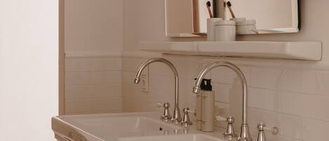 A bathroom with a double sink, wooden vanity, and a large mirror above the sink.