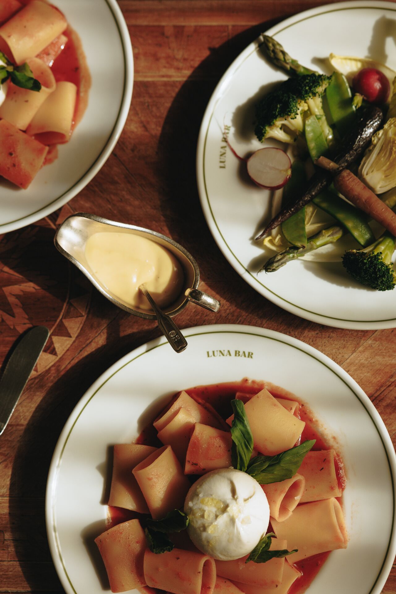 Three plates of food on a wooden table.
