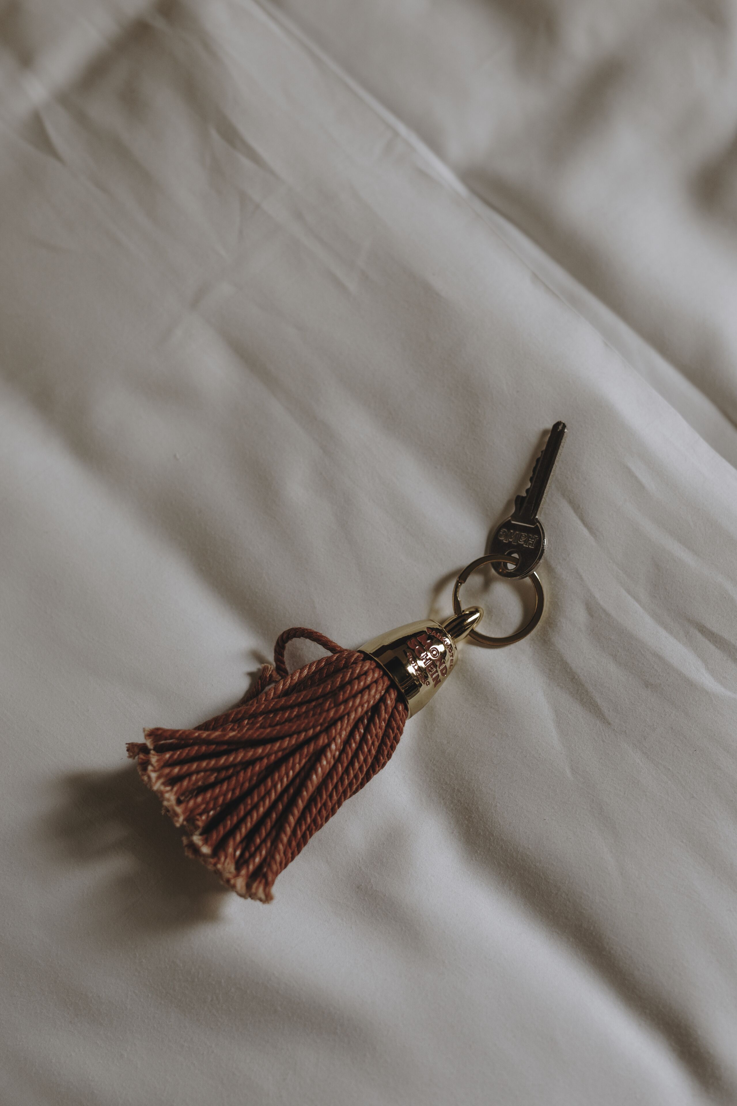 A keychain with a tassel on a white fabric surface.